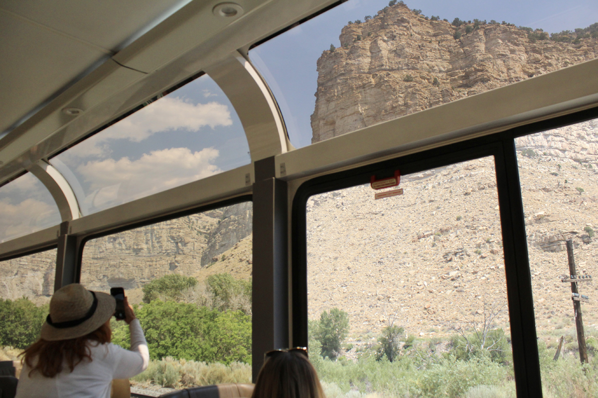 Person taking photo of mountain through passenger car window