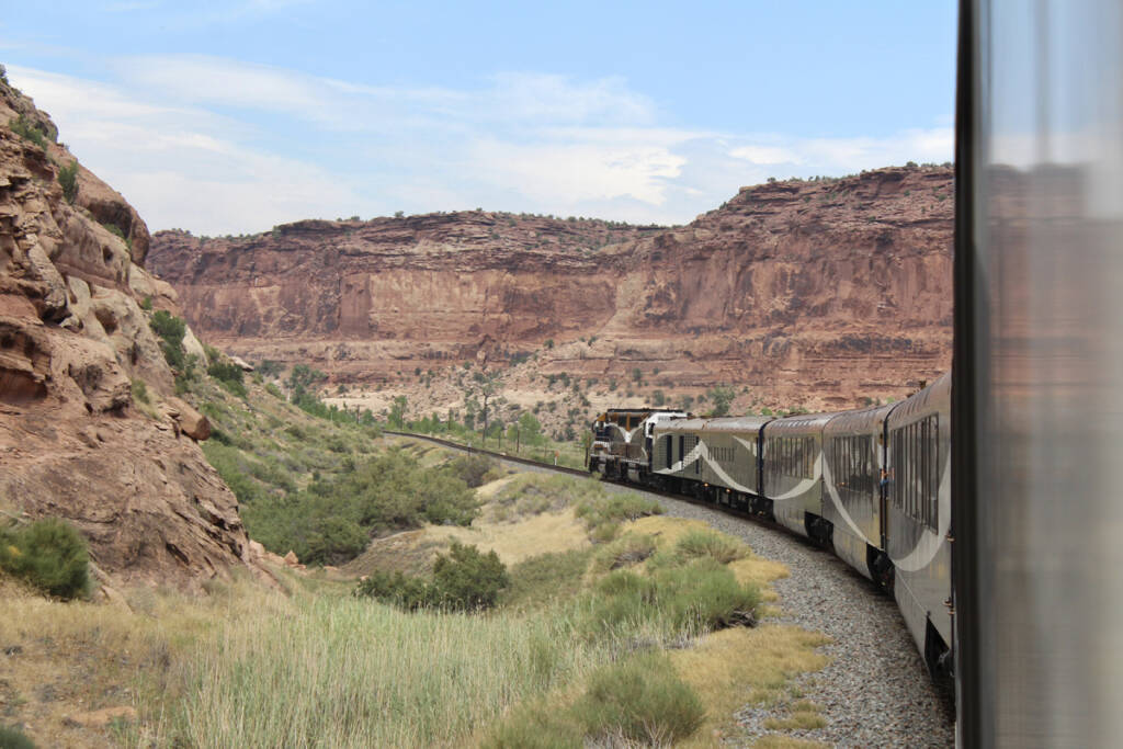 Train traveling through area of red rock hills