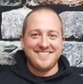 Head shot of man standing against stone wall