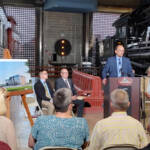 Group of people listening to speaker in railroad museum building