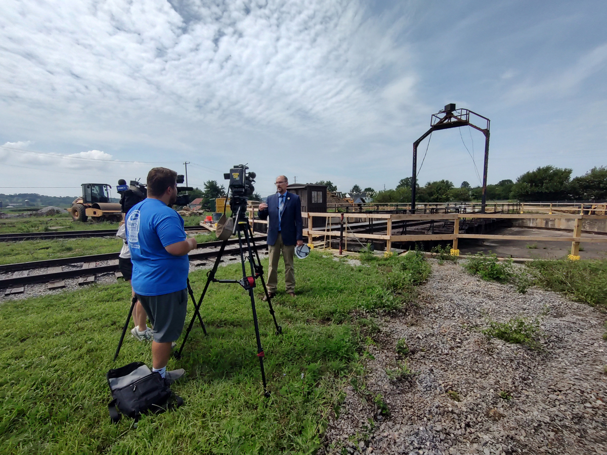 Man speaking to TV camera with turntable in background