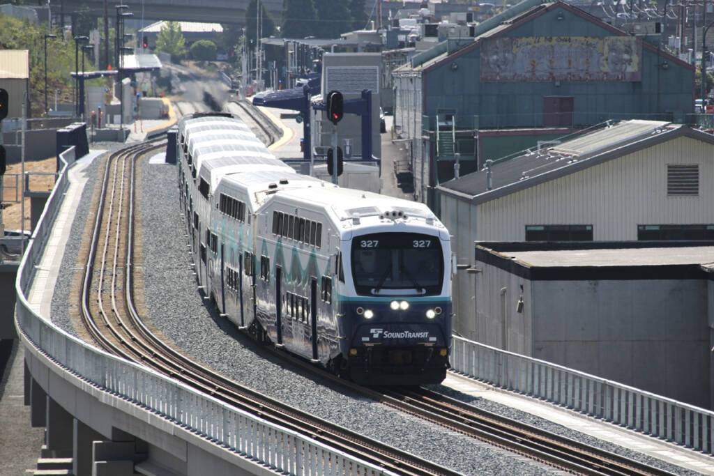 Commuter train led by cab car on concrete bridge