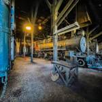 A steam locomotive sits inside a roundhouse