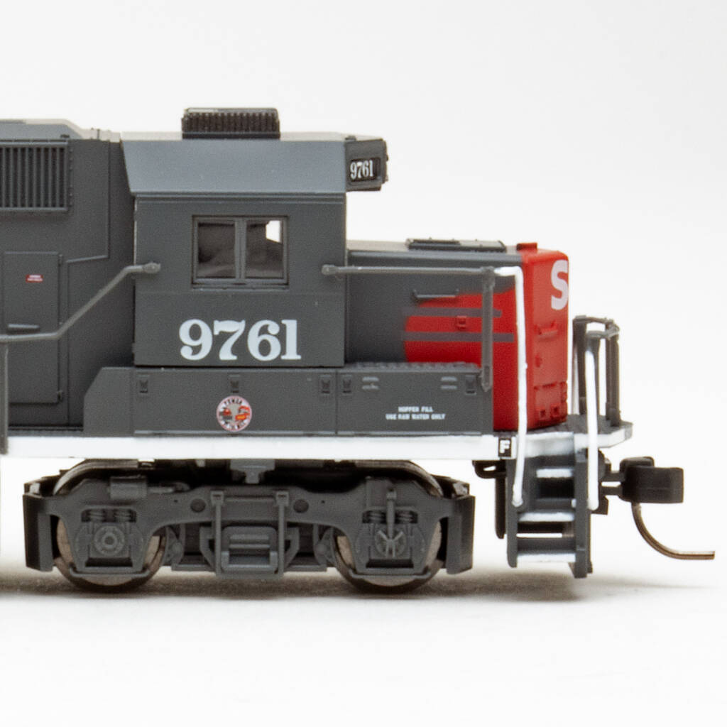 Color photo showing side view of N scale hood unit painted scarlet and gray on white background.