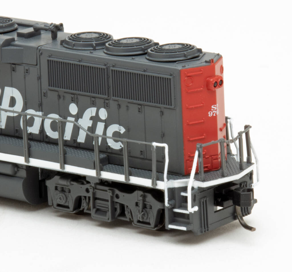 Color photo showing rear of long hood on N scale diesel painted scarlet and gray on white background.