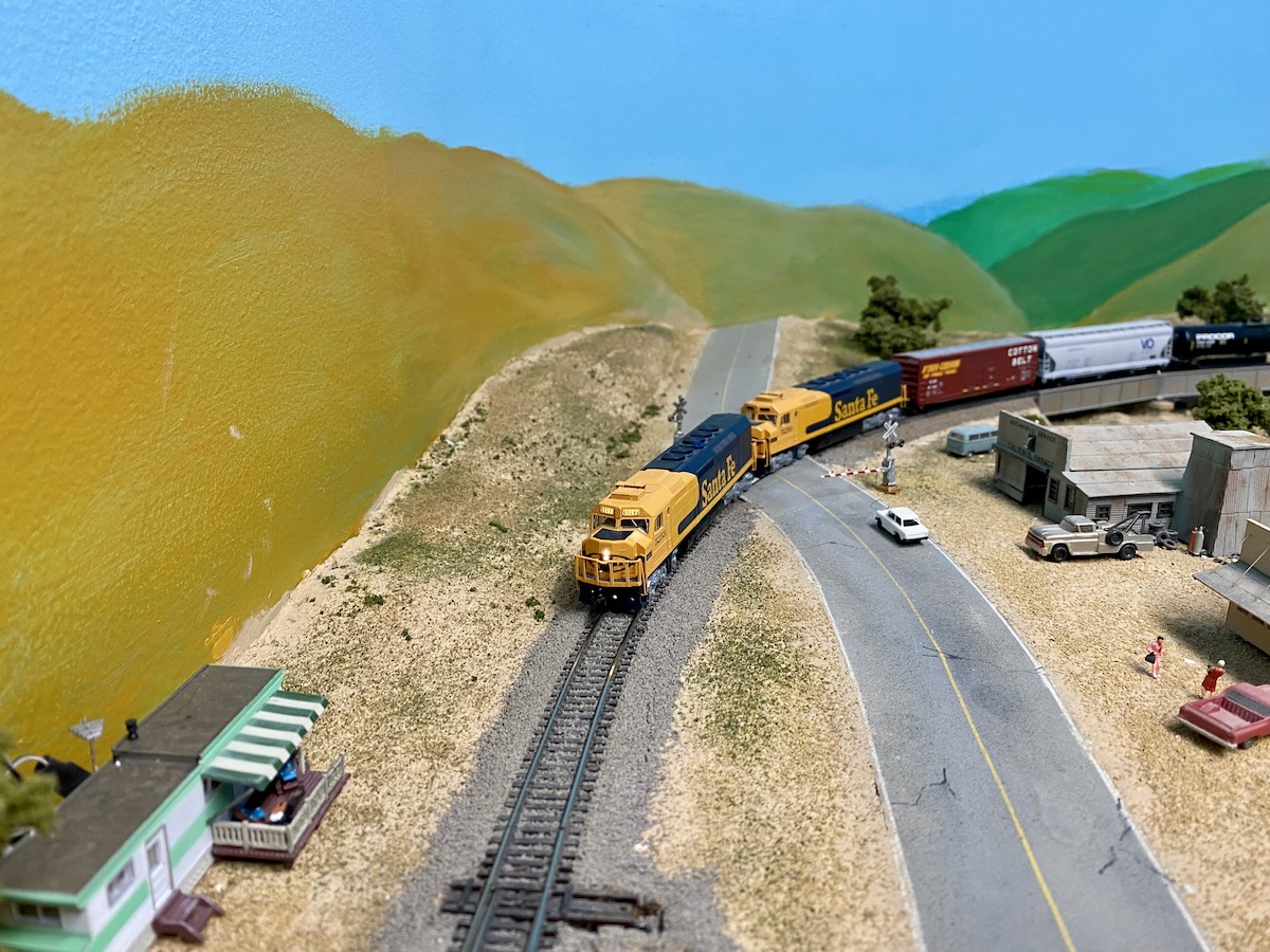 N scale freight trains rounds a curve at a railroad crossing
