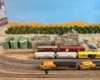 N scale freight train passes by a small town with industry