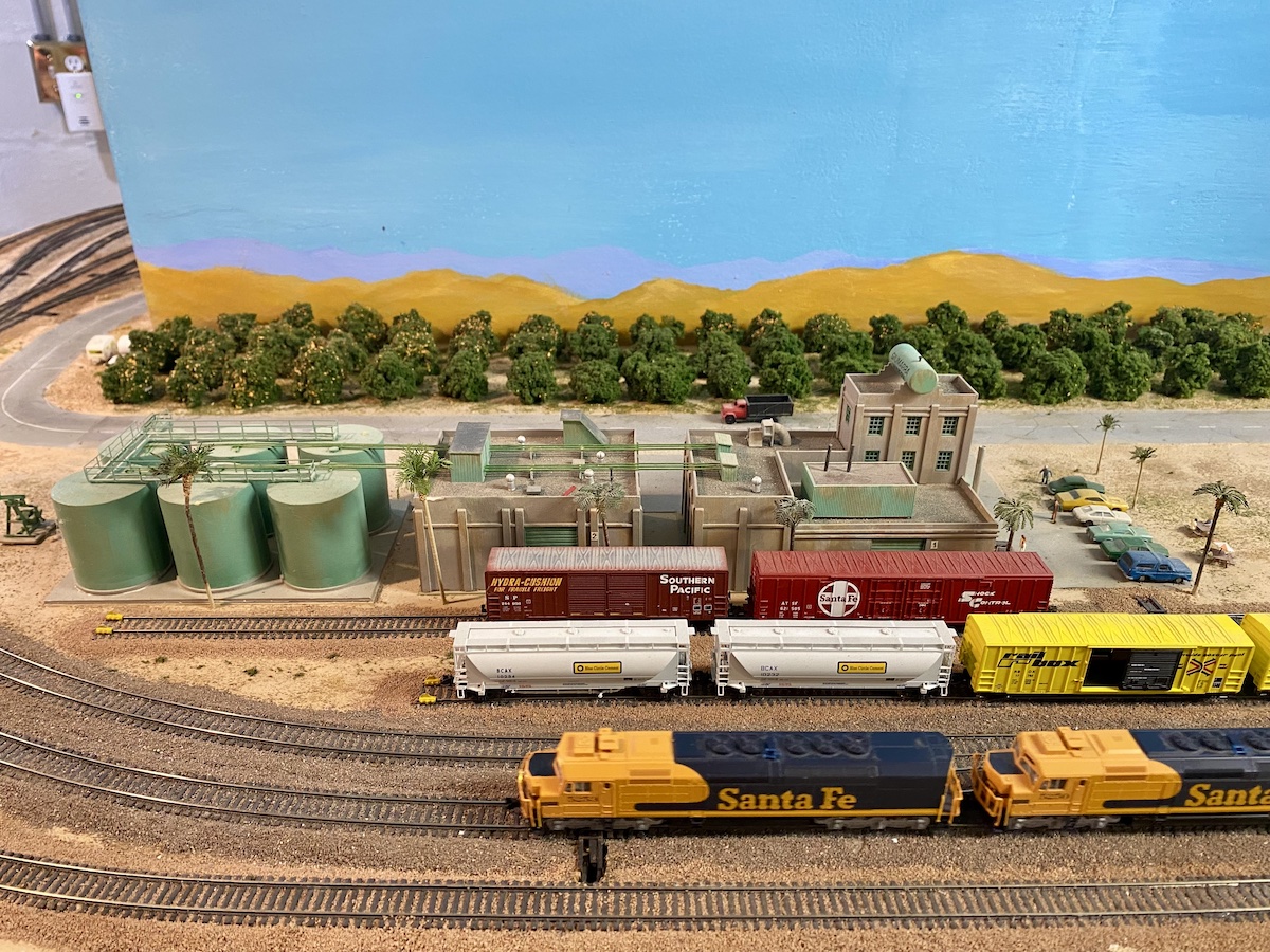 N scale freight train passes by a small town with industry