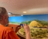 Individual taking pictures of a N scale train traversing a loop