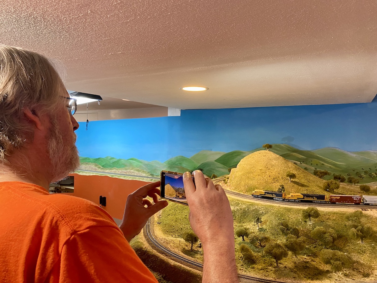 Individual taking pictures of a N scale train traversing a loop