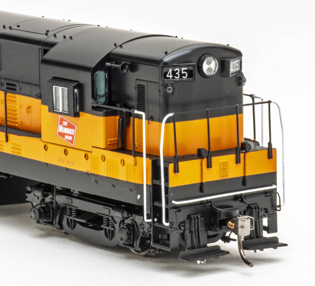 Color photo showing front of HO scale diesel painted orange and black on white background.
