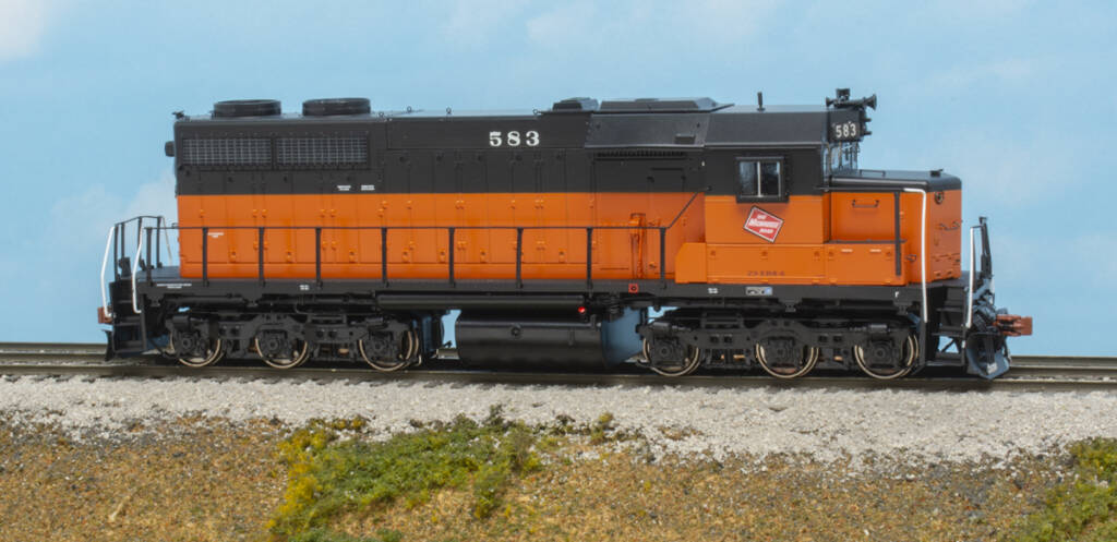 Color photo of HO scale EMD hood unit painted orange and black on scenicked base with sky backdrop.