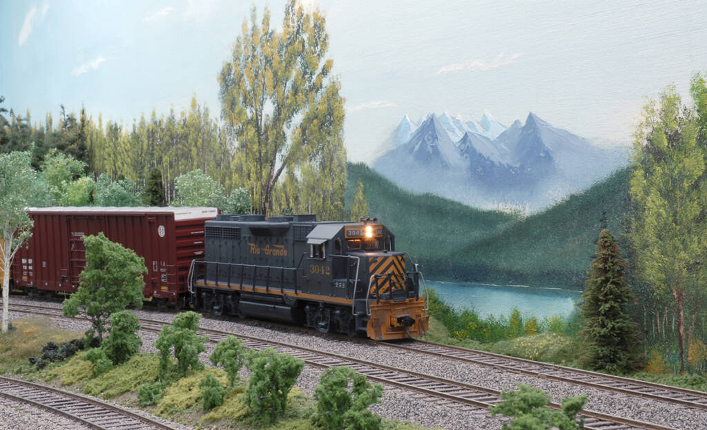A diesel locomotive with a mountain in the background on a model railroad layout
