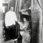 A Pullman Porter serves a glass of water to a woman in a sleeping car berth