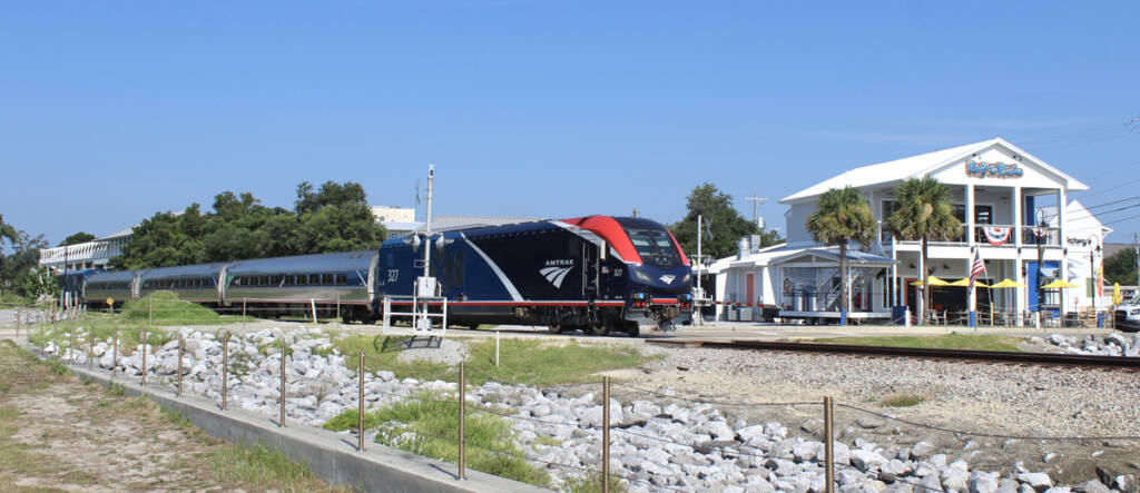 Passenger train passing white two-story building
