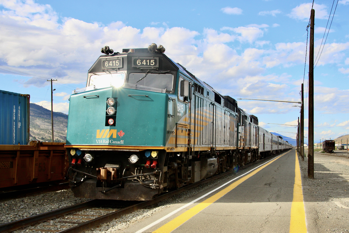 Long passenger train with three locomotives at station