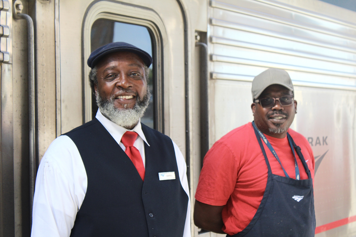 Two men standing outside passenger car