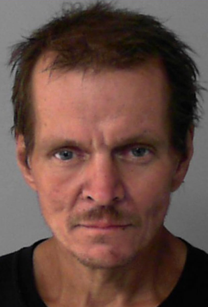 Booking photo of scowling man