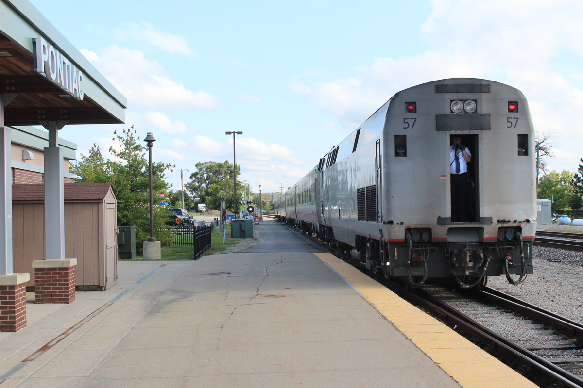 Locomotive at back of passenger train with crew member in back door
