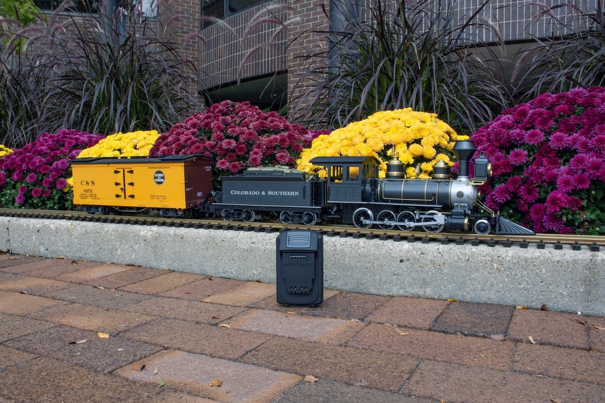 Large steam locomotive and caboose with a power tool battery