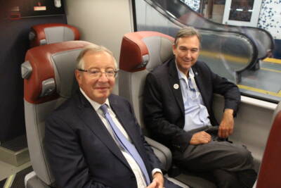 Two men sitting in a passenger train car.