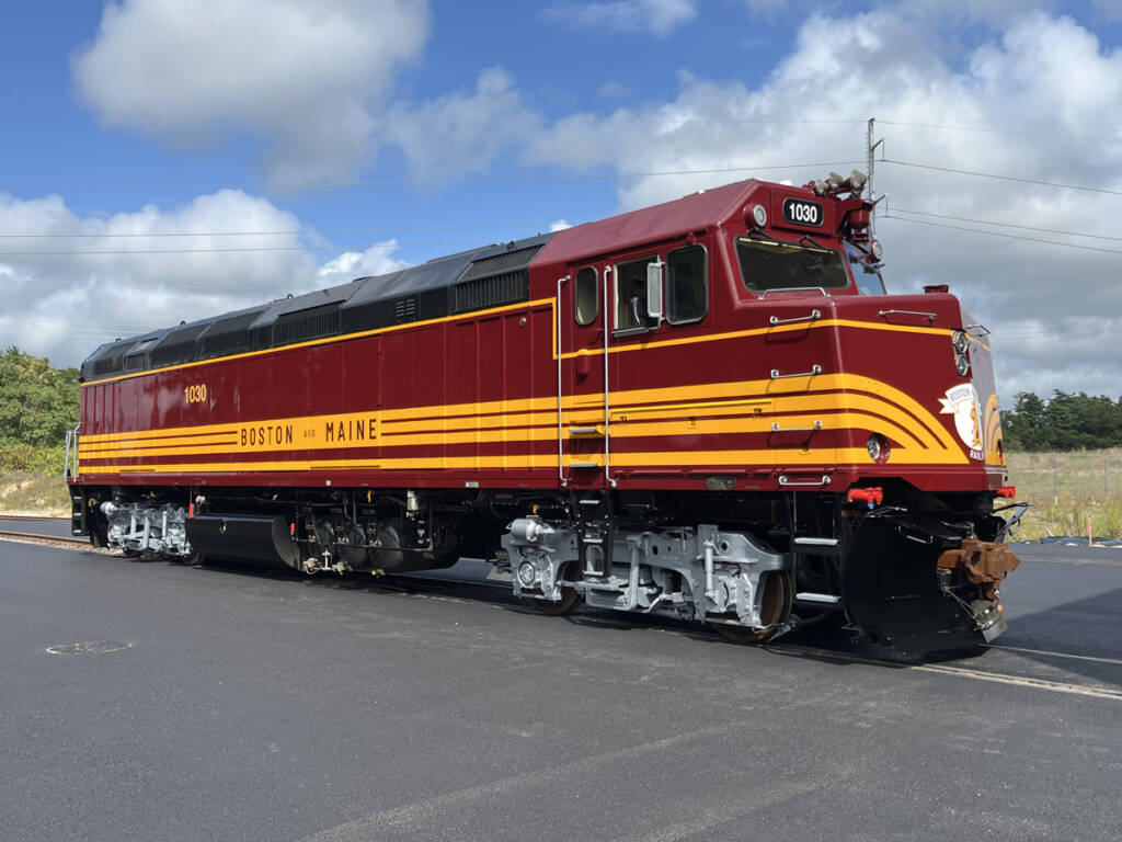 Maroon and gold commuter-rail locomotive with silver trucks