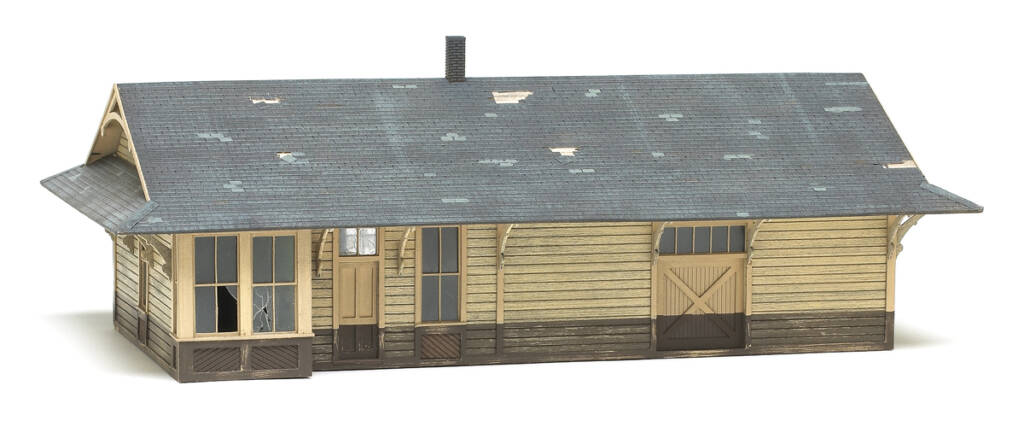 Color photo of HO scale weather-beaten depot painted tan and brown with gray roof on white background.