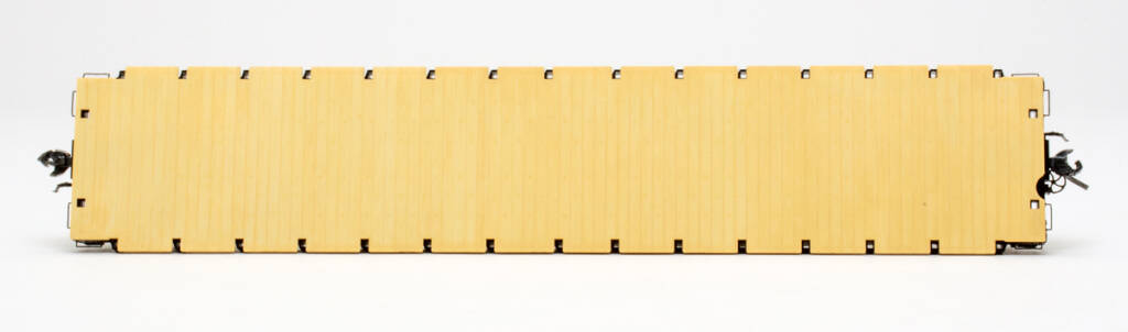 Color photo showing tan flatcar deck on HO scale flatcar on white background.