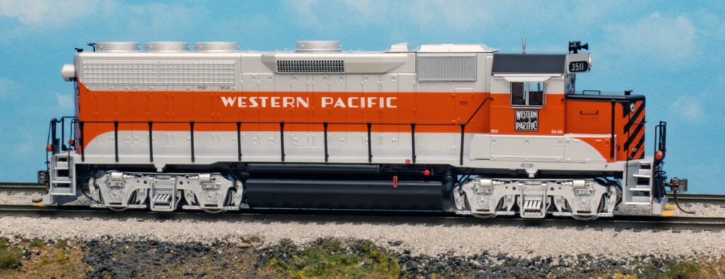 Color photo of HO scale four-axle road switcher painted silver, orange, and black on scenicked base