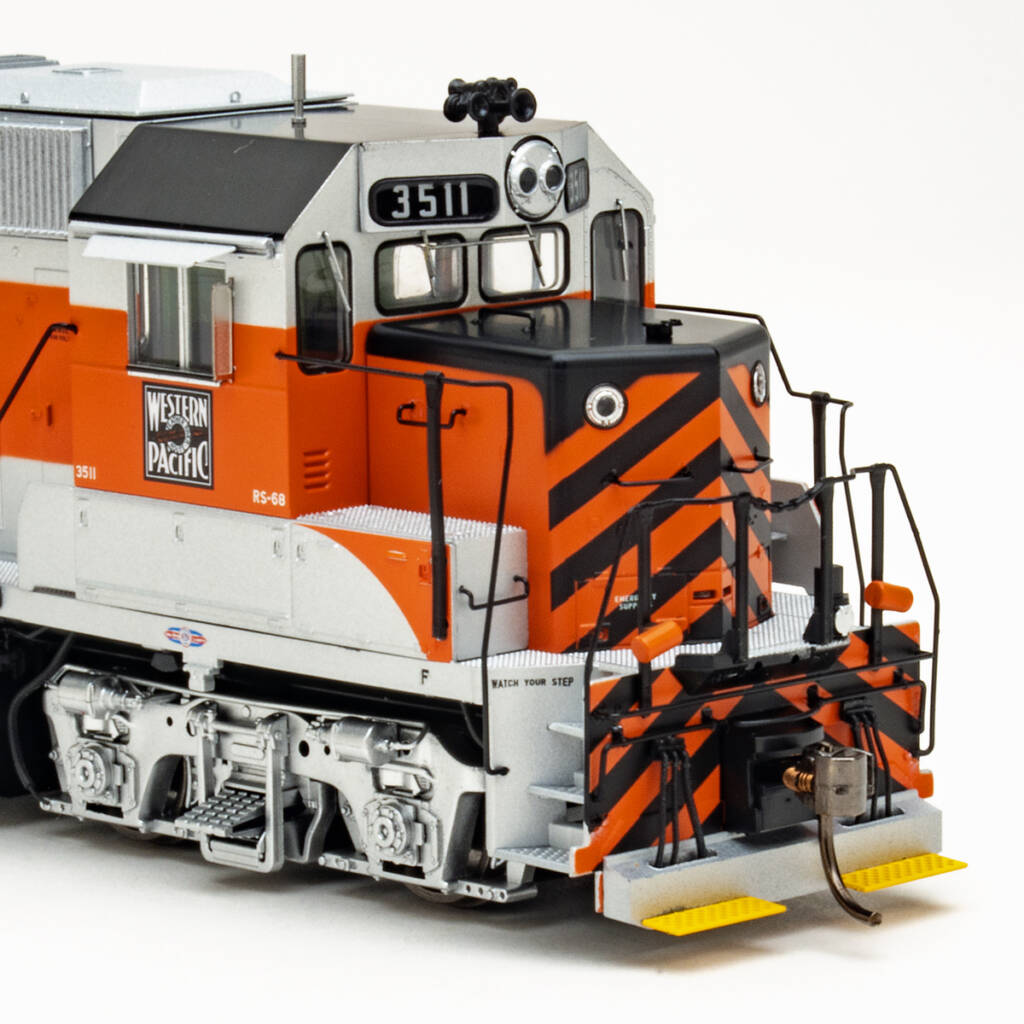 Color photo showing nose of HO scale four-axle road switcher painted silver, orange, and black on white background