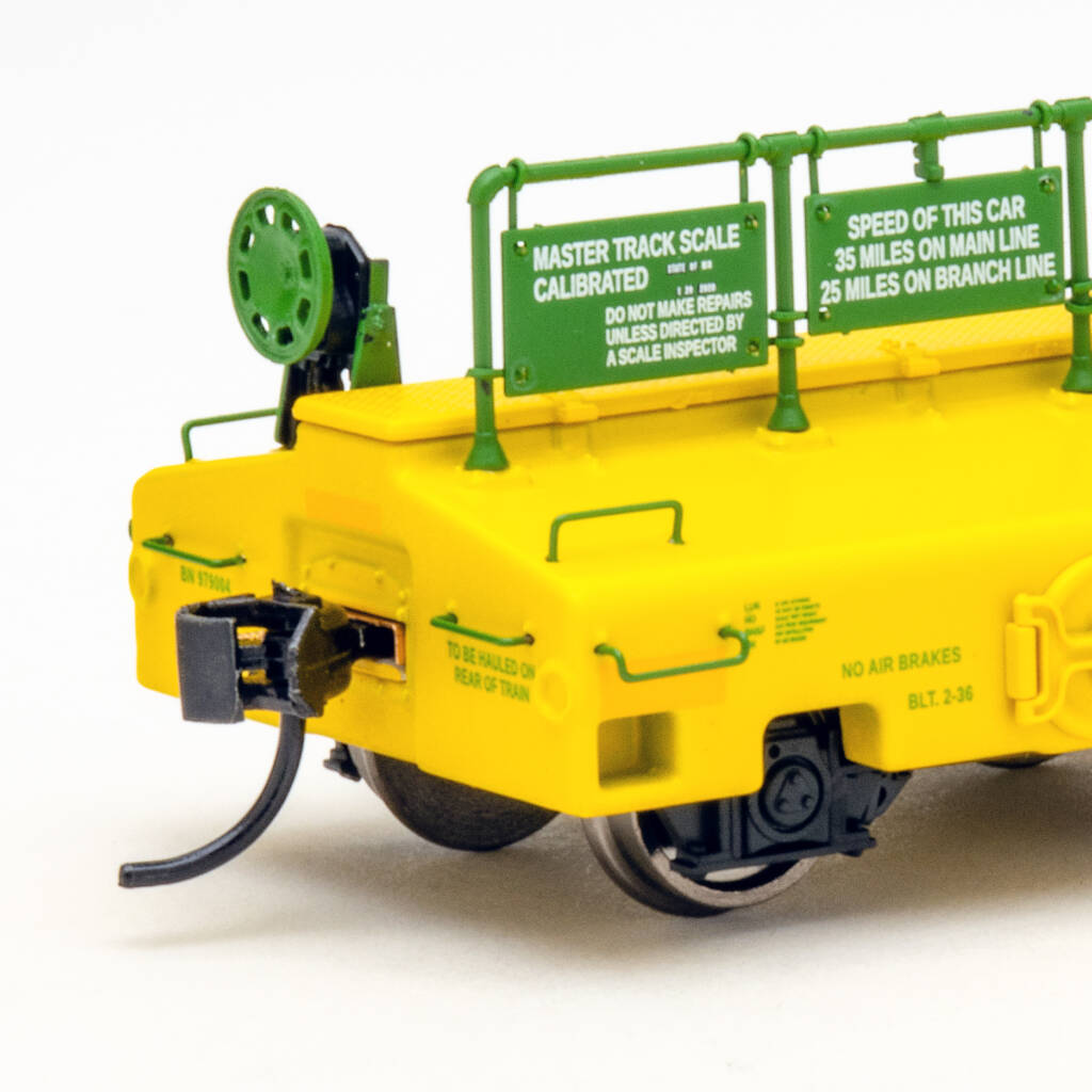 Color photo of HO scale test car painted green and yellow on white background