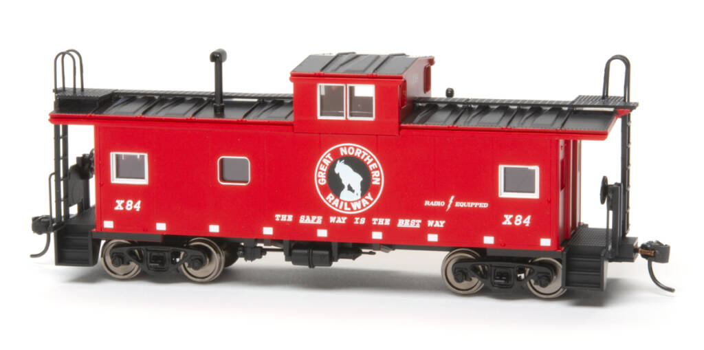 Color photo of HO scale caboose painted red and black with black and white graphics on white background.