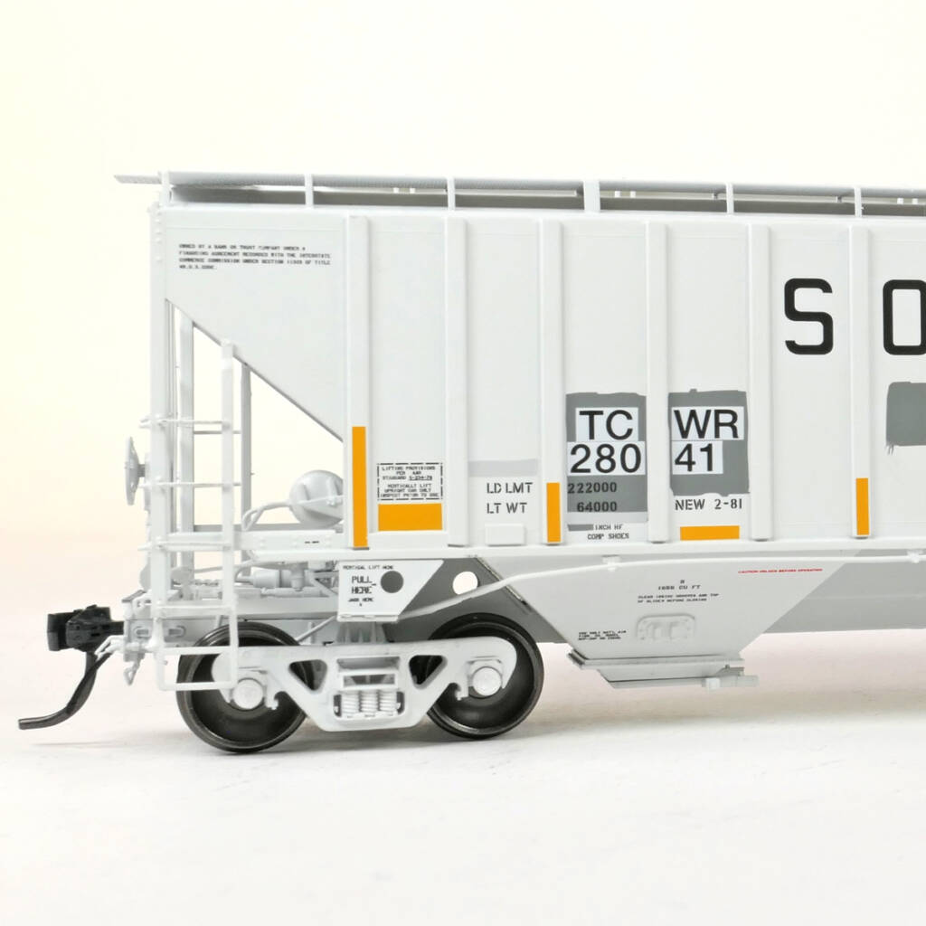 Color photo showing B end of HO scale three-bay covered hopper painted gray with black and yellow graphics on white background