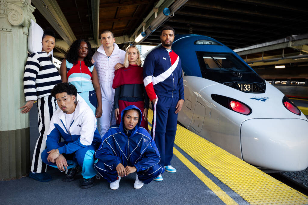 Group of fashion models next to new Amtak Acela train.