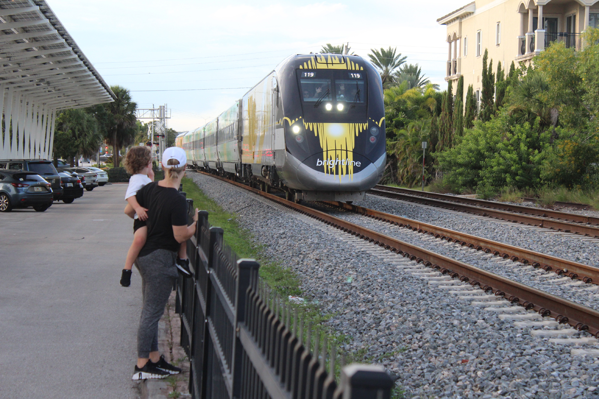 Woman holding child watching train pass