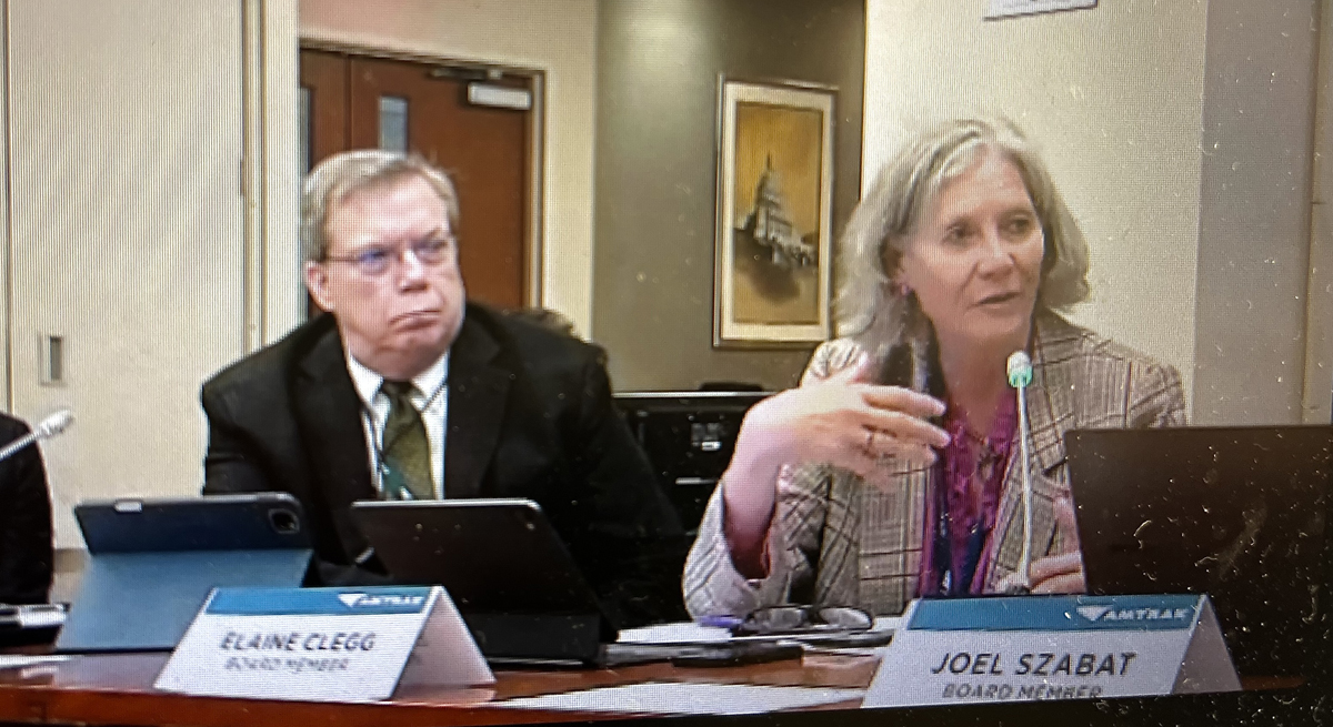 Woman speaking into microphone as man looks on