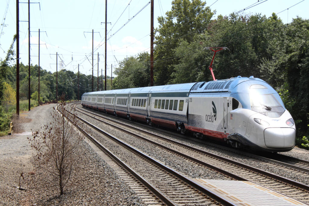Blue and white streamline passenger train on straight track after curve