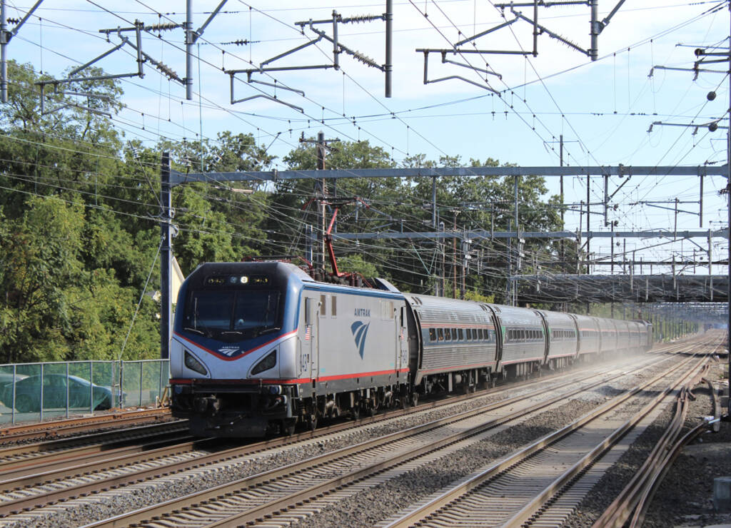 Passenger train pulled by electric locomotive on long straight