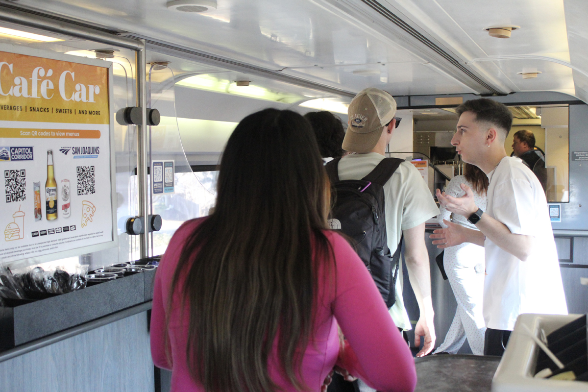 People lined up in passenger car with "Cafe car" sign visible.