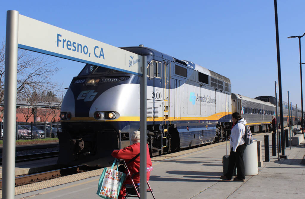 Passenger train with "Fresno, Calif." station sign in foreground