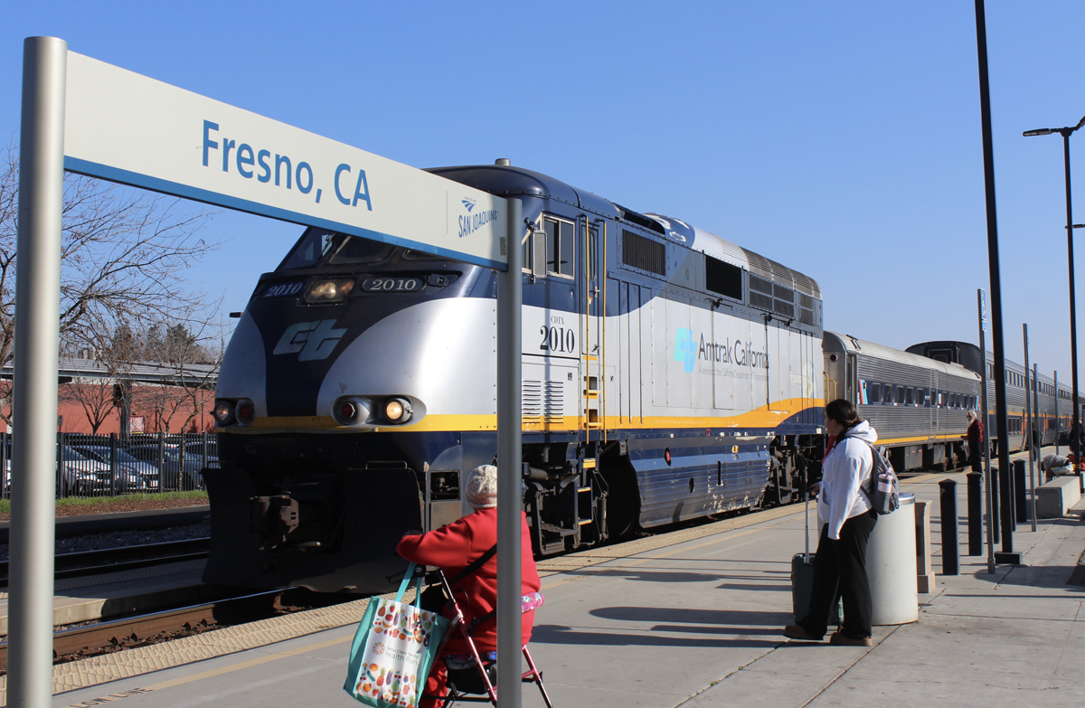 Passenger train with "Fresno, Calif." station sign in foreground