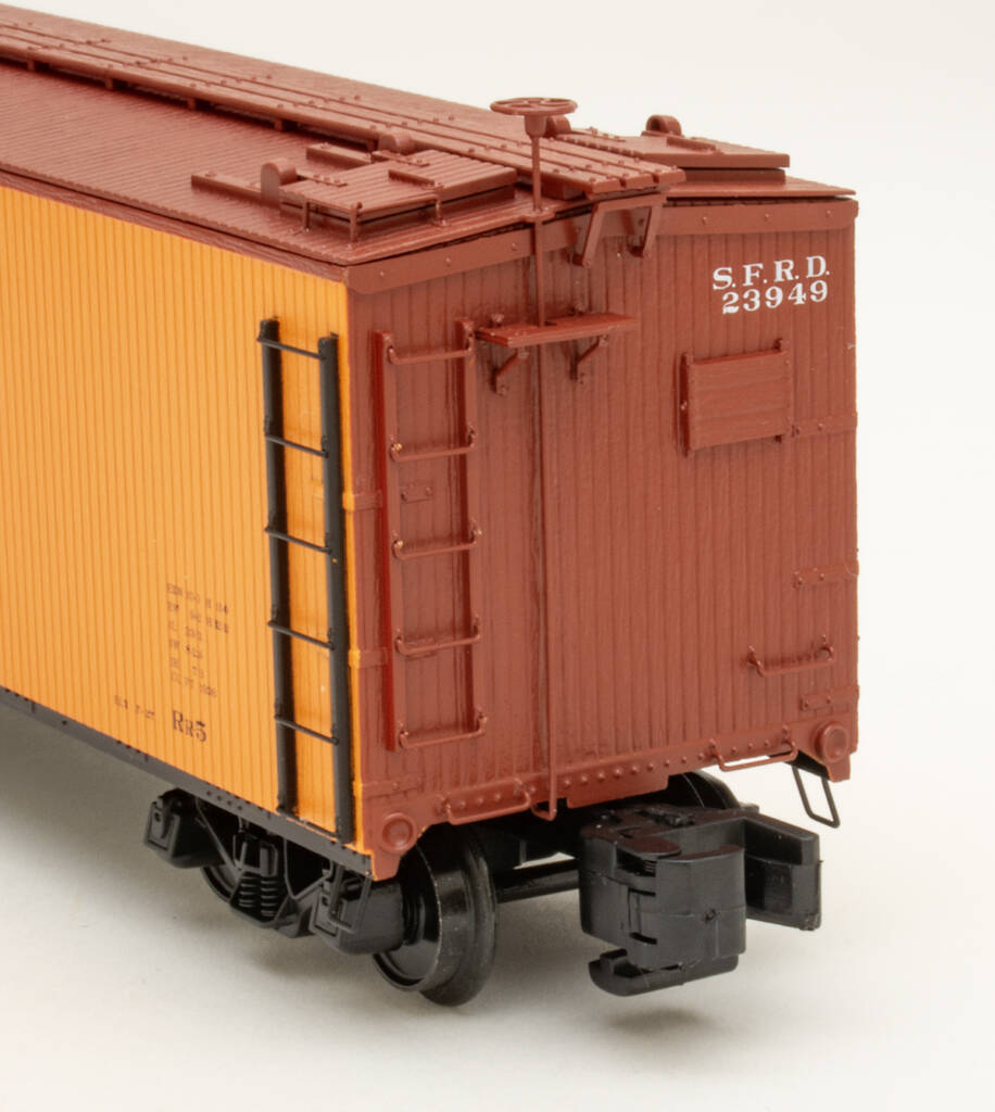 Color photo showing B end details of S gauge wood refrigerator car painted yellow-orange, mineral brown, and black on white background.