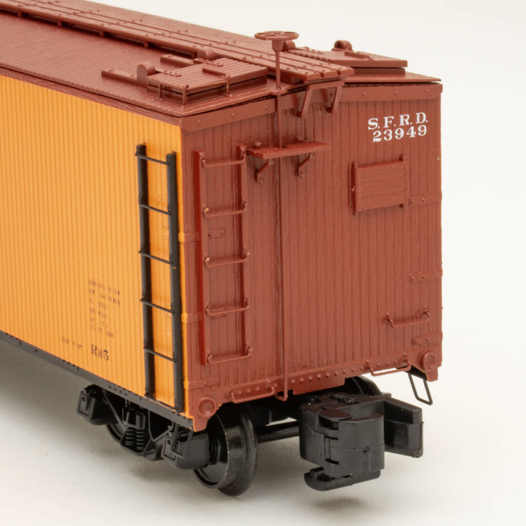 Color photo showing B end details of S gauge wood refrigerator car painted yellow-orange, mineral brown, and black on white background.