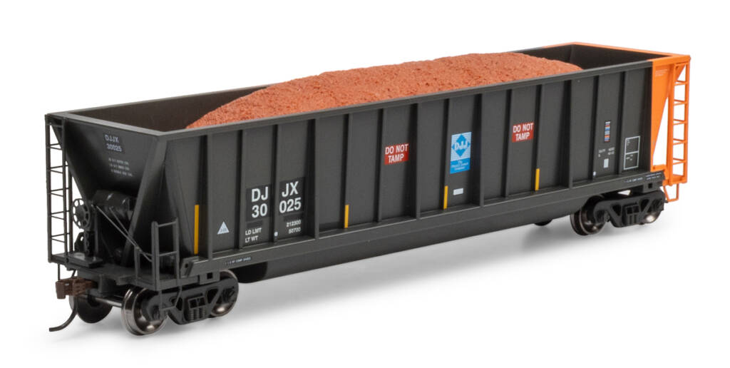 Color photo of HO scale bathtub gondola painted faded black with orange rotary end with simulated scrap metal load and red, white, blue, and yellow graphics on white background.