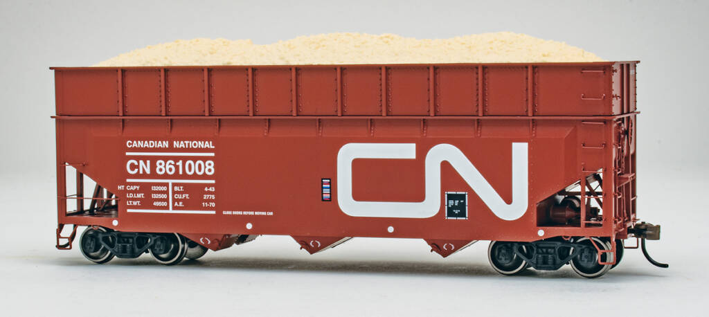 Color photo of HO scale wood-chip hopper painted mineral red with white and black graphics on white background 