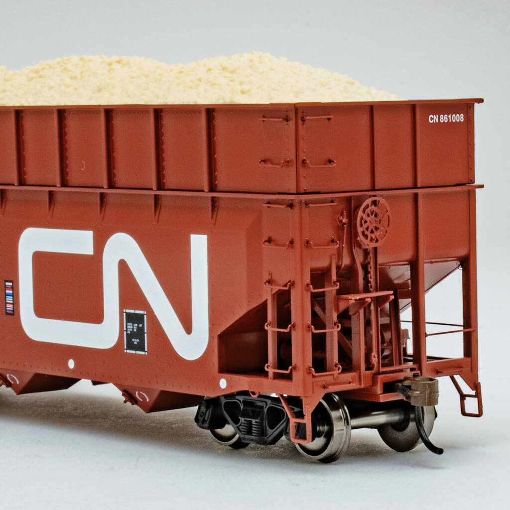 Color photo showing B end of HO scale wood-chip hopper painted mineral red with white and black graphics on white background