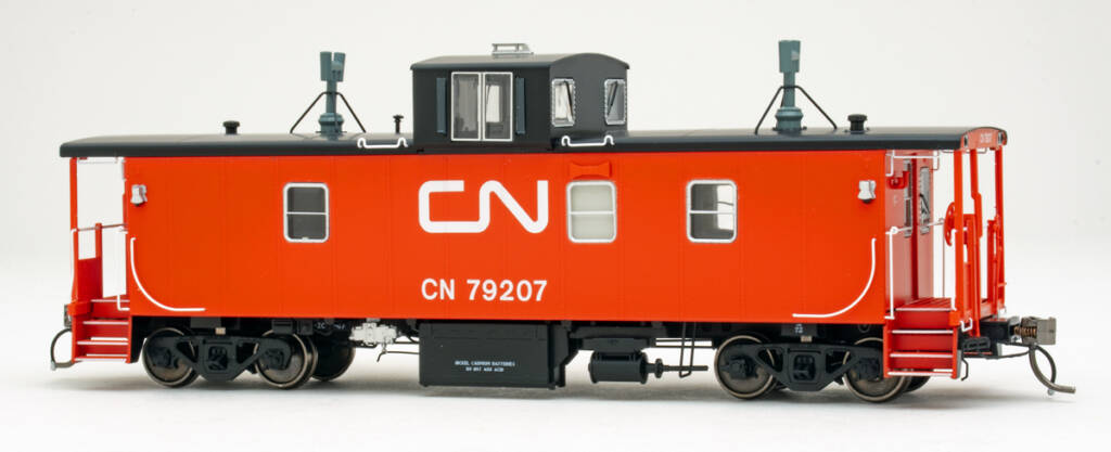 Color photo of HO scale caboose painted red and black with white graphics on white background.