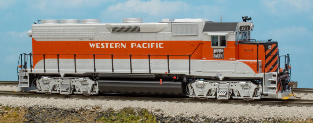 Color photo of HO scale hood unit painted aluminum, orange, and black on scenicked base with sky background.