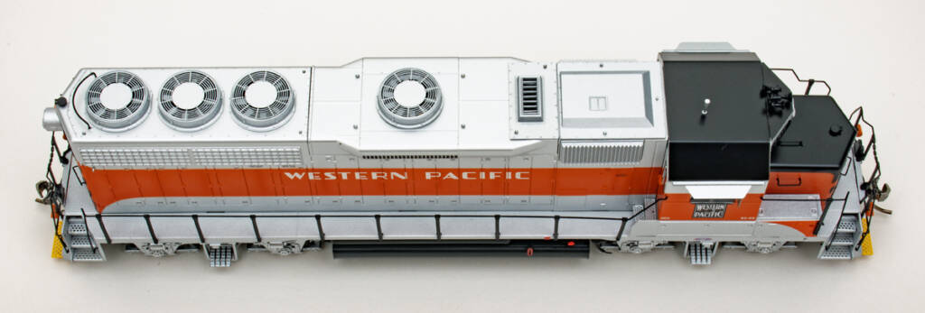 Color photo showing rooftop details of HO scale diesel painted aluminum, orange, and black on white background.