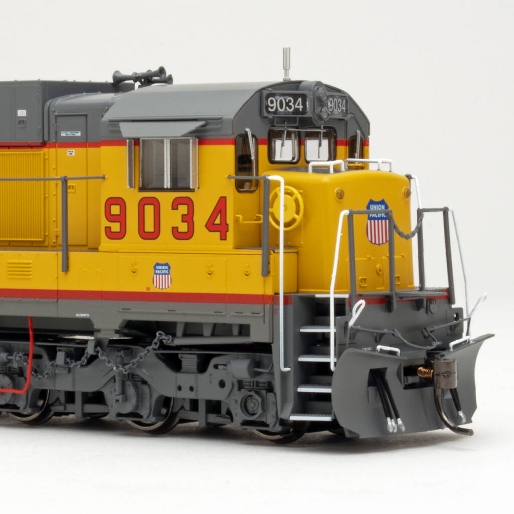 Color photo showing front of HO scale diesel locomotive painted yellow and gray with red, white, and blue graphics on white background